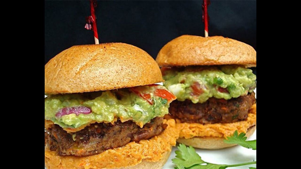 Caramelized onions are folded into black bean patties and then topped with homemade guacamole for vegan-friendly Mexicali sliders.