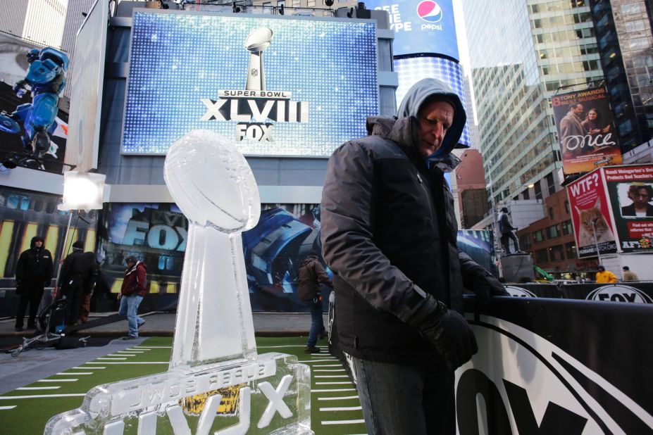 A worker in Times Square moves a barrier January 28 near an ice sculpture that is modeled after the Lombardi Trophy.