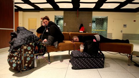 Two women are stranded at Louis Armstrong New Orleans International Airport on January 28 after flights were canceled due to the weather.