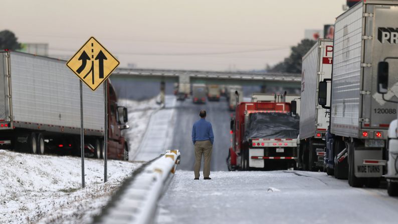 A man stands on the frozen roadway January 29 as he waits for traffic to clear along Interstate 75 in Macon, Georgia.