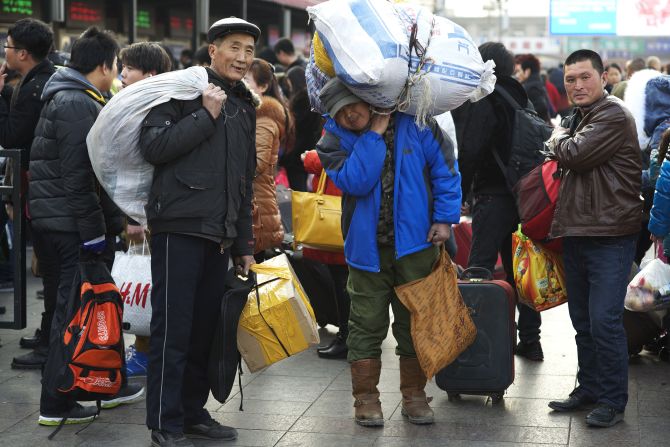 (L to R) Tang Zhiyuan, 61, Tang Zhongliang, 58, and Ding Wendong, 32, came to Beijing a year ago from Haicheng, Liaoning province. They work in logistics. Mr. Ding's bag is full of new clothes he bought for his family members. Mr. Tang, balancing a huge bag on his shoulder, bought some Beijing roast duck for the New Year's Eve dinner. 
