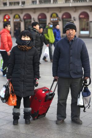 Du Shuxiang (L), 46, came to Beijing from Heilongjiang province three years ago. She works in a pickle factory. She is accompanied by Wang Zhiyou, a sanitation worker who came to Beijing seven years ago from the same town in Heilongjiang province as Du. Wang will wait to go home after New Year's Eve as he couldn't get a ticket to travel in advance. 