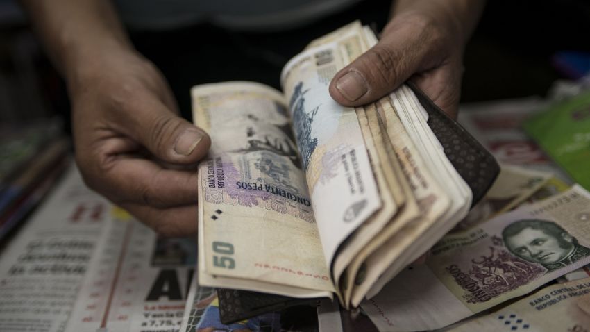 A newsstand owner counts Argentine pesos in Buenos Aires on January 24, 2014. Argentina on Friday lifted restrictions in place since 2011 that limited the purchase of foreign currency, a day after the peso suffered its worst single-day dive since the 2002 financial crisis. The government has decided "to authorize the purchase of dollars for holding or savings, " said Jorge Capitanich, President Cristina Kirchner's cabinet chief. The restrictions had always been temporary and had served their purpose. TOPSHOTS/AFP PHOTO / LEO LA VALLELEO LA VALLE/AFP/Getty Images