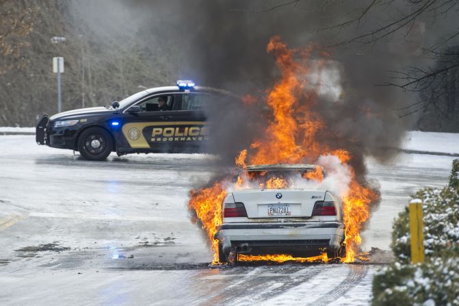 Police monitor a fire January 29 in a vehicle left overnight by a motorist who was stranded in Brookhaven, Georgia.