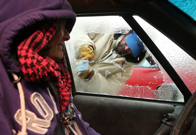 Sue Morrison watches as Chris McAdams scrapes ice from her car on January 29 in Panama City Beach, Florida.