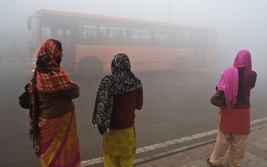 Indian commuters wait for a bus on a polluted morning in New Delhi.