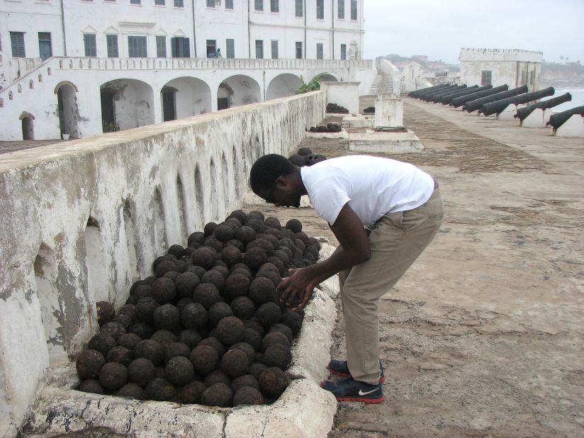 Clark examines original cannonballs, stacked near the defense cannons at Cape Coast Castle. The Dutch considered the castle, with its high, thick walls and fierce guns impossible to capture, even though they occupied Elmina castle just a few kilometers away.