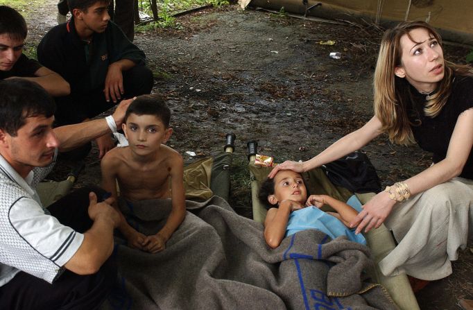 Ossetians comfort children during the rescue operation at Beslan school. Around 700 local residents were wounded in the hostage siege.