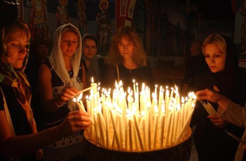 Russian women light candles after a special memorial service at a church on September 7, 2004.