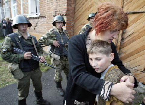 A mother hugs her son in front of soldiers cordoning off the school building.