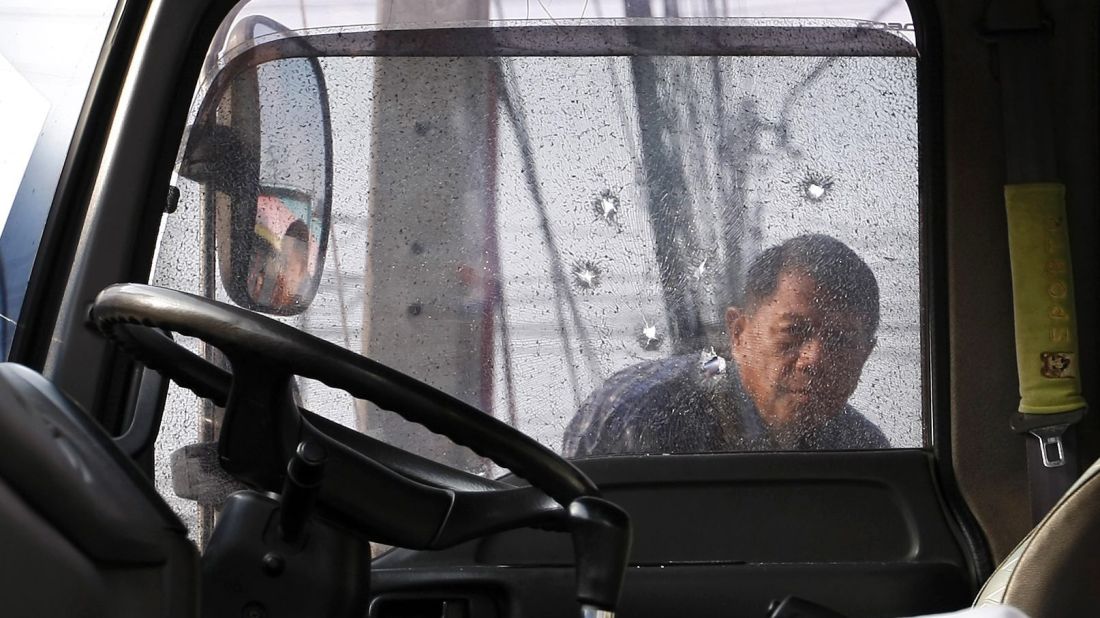 An anti-government protester inspects bullet holes in a window of his comrade's truck.