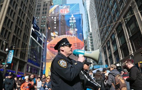 A New York City police officer use a bull horn to direct pedestrians visiting Super Bowl Boulevard on February 1 in New York.