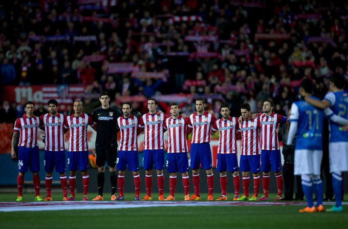 Players from both sides link arms during a minute's silence for playing  and coaching legend Aragones following his death Saturday.