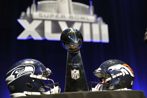 The helmets of the competing Super Bowl teams Seattle and Denver flank the iconic Vince Lombardi trophy.