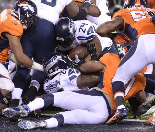 Marshawn Lynch (no 24) forces his way through a pack of players to score the opening touchdown of the game for the Seahawks.