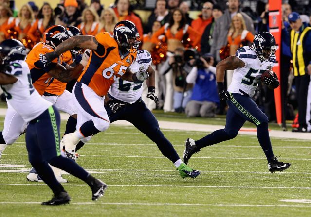 Smith has intercepted Manning's misplaced pass and is charging towards the end zone to score a touchdown.