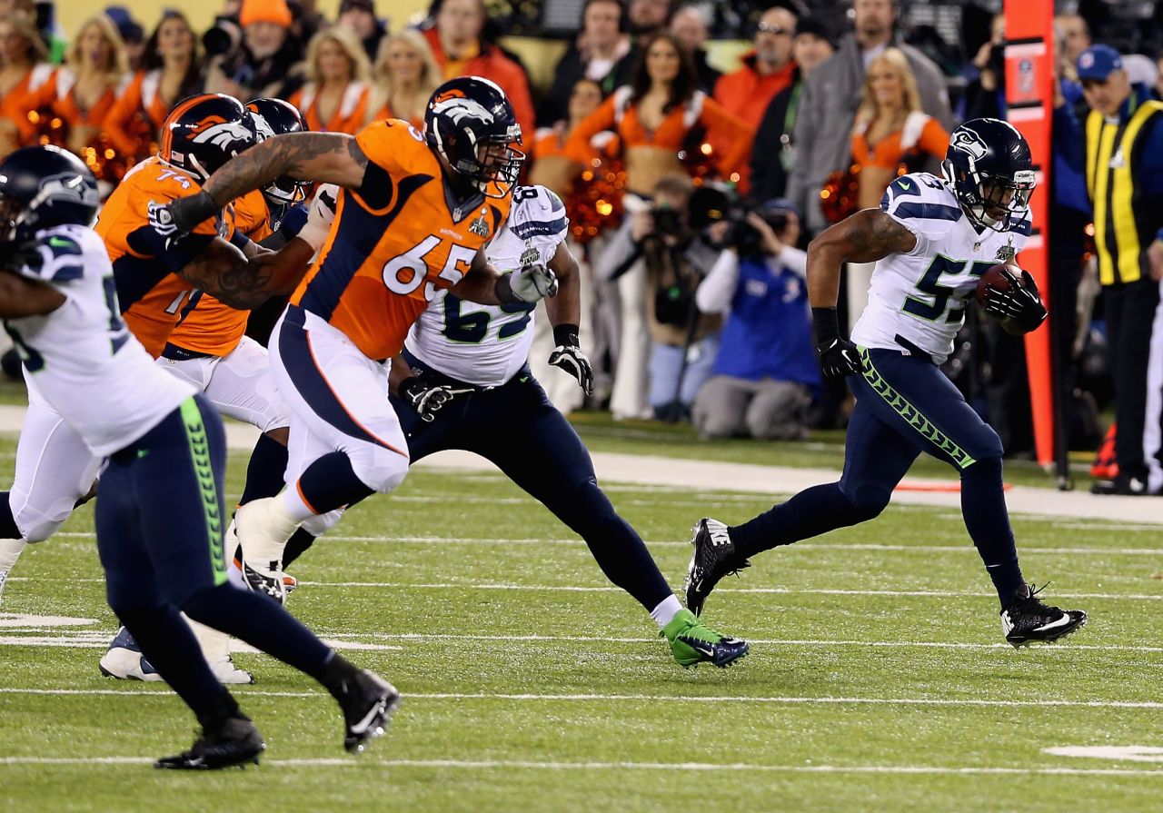 Smith has intercepted Manning's misplaced pass and is charging towards the end zone to score a touchdown.