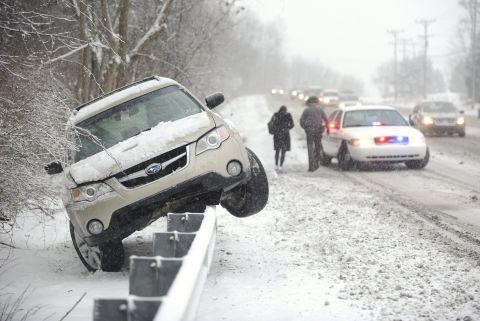 A police officer walks a woman to his vehicle after her car slid off the road and was stranded on top of a guardrail February 3 in State College, Pennsylvania.