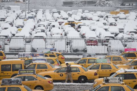 A taxi driver walks beside his vehicle in the parking lot of Terminal B at LaGuardia Airport on February 3.