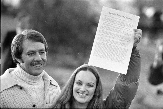 Hearst holds up the executive grant of clemency as she leaves prison on February 1, 1979. With her is her fiance and former bodyguard, Bernard Shaw.