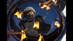 A woman is reflected in a basin as she lights incense at a temple in Beijing on Tuesday, February 4.