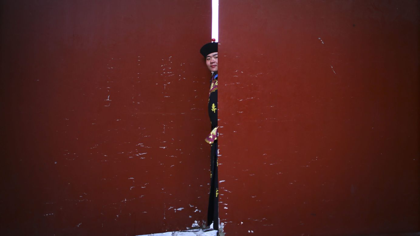 A performer peeks through a door before the start of a ritual at a temple in Beijing on February 4.
