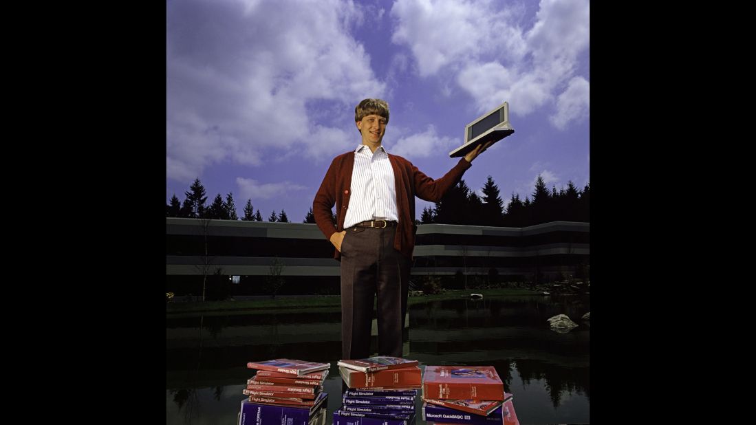 Gates poses outdoors with Microsoft's first laptop in 1986 at the new 40-acre corporate campus in Redmond, Washington. In March 1986, Microsoft held an initial public offering of 2.5 million shares. By the end of the year, Gates became a billionaire at the age of 31. Microsoft was the first company to dominate the personal computer market with its MS-DOS system and subsequently the Windows platform. 