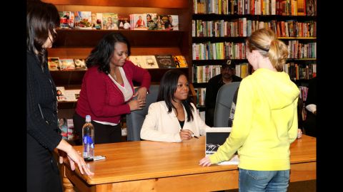 American gymnast Gabby Douglas signs autographs while her mother, Natalie Hawkins, stands nearby at a Skokie, Illinois, bookstore in 2013.