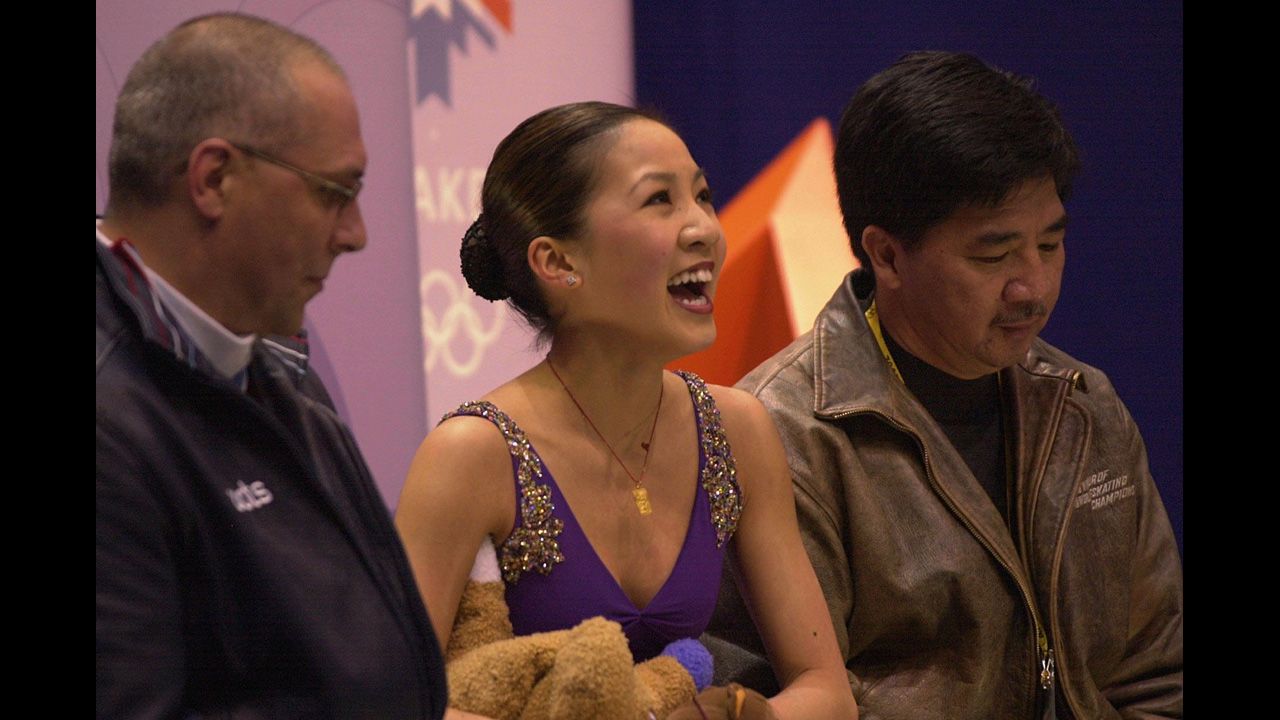 U.S. figure skater Michelle Kwan smiles to the crowd after competing during the 2002 Olympic Games in Salt Lake City. At right is her father, Danny.