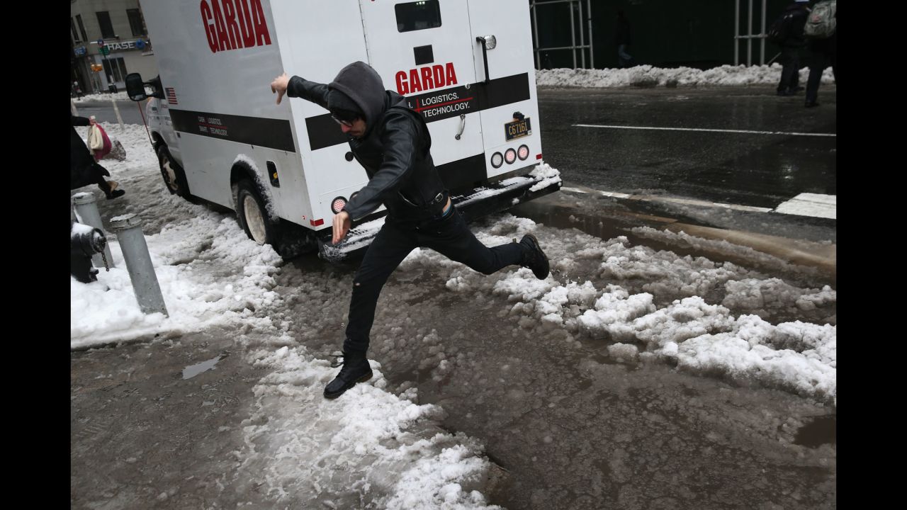 A man leaps over a slushy curb in New York City on February 5.