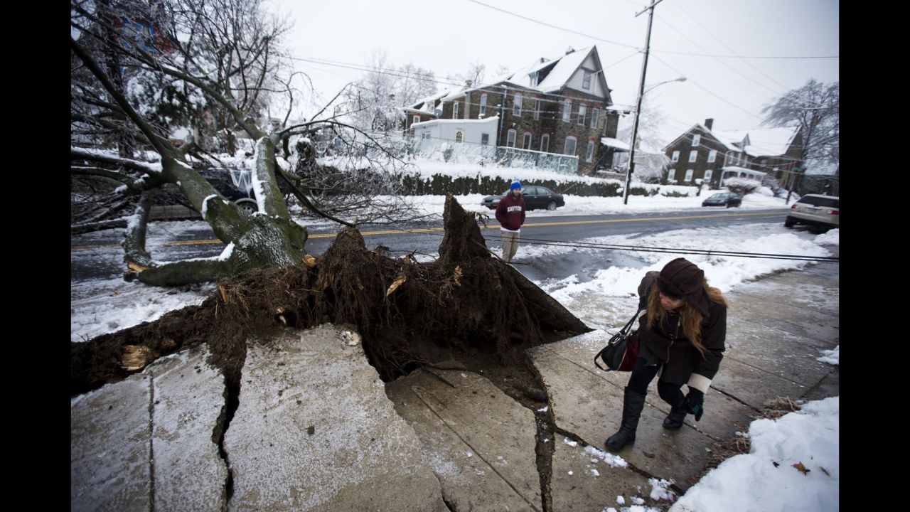 A woman ducks under a utility line next to a downed tree in Philadelphia on February 5.