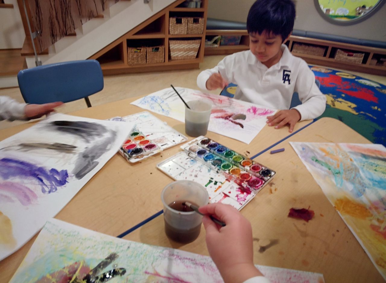 A pre-kindergarten student wears Google Glass while painting with watercolors for a community service project. He documented how crayon and watercolors interact, and the work was eventually sent to be place mats at a local Ronald McDonald House.  
