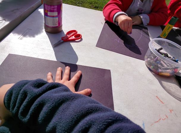 Un estudiante de jardín infantil trabaja para trazar su propia mano y registrar el proceso con Glass. Trabajó en un árbol de otoño con papel y colores pastel durante la celebración del festival de otoño.