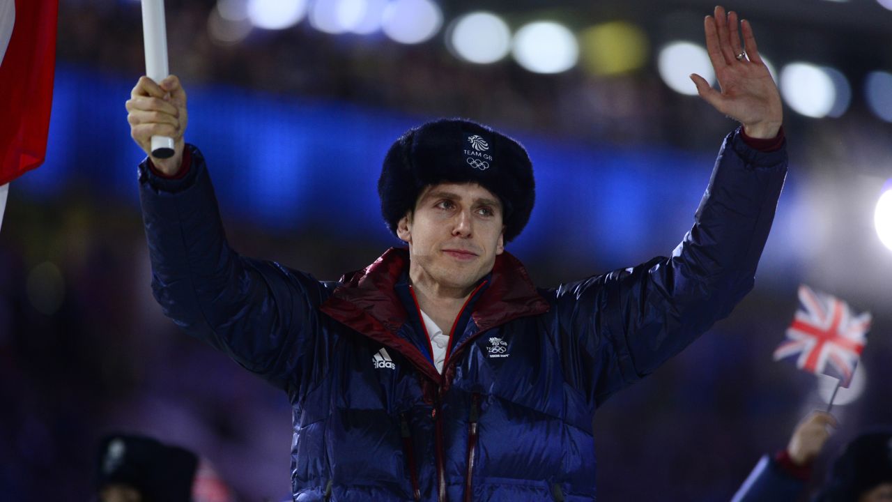 Great Britain's flag bearer, short-track speed skater Jon Eley, waves as he leads the British delegation.