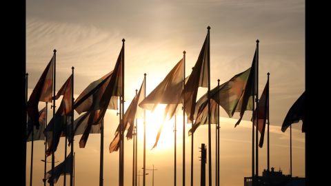 Before the start of the ceremony, the sun sets behind delegation flags.