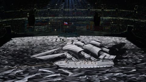 People move as a boat is projected across the floor of the stadium.