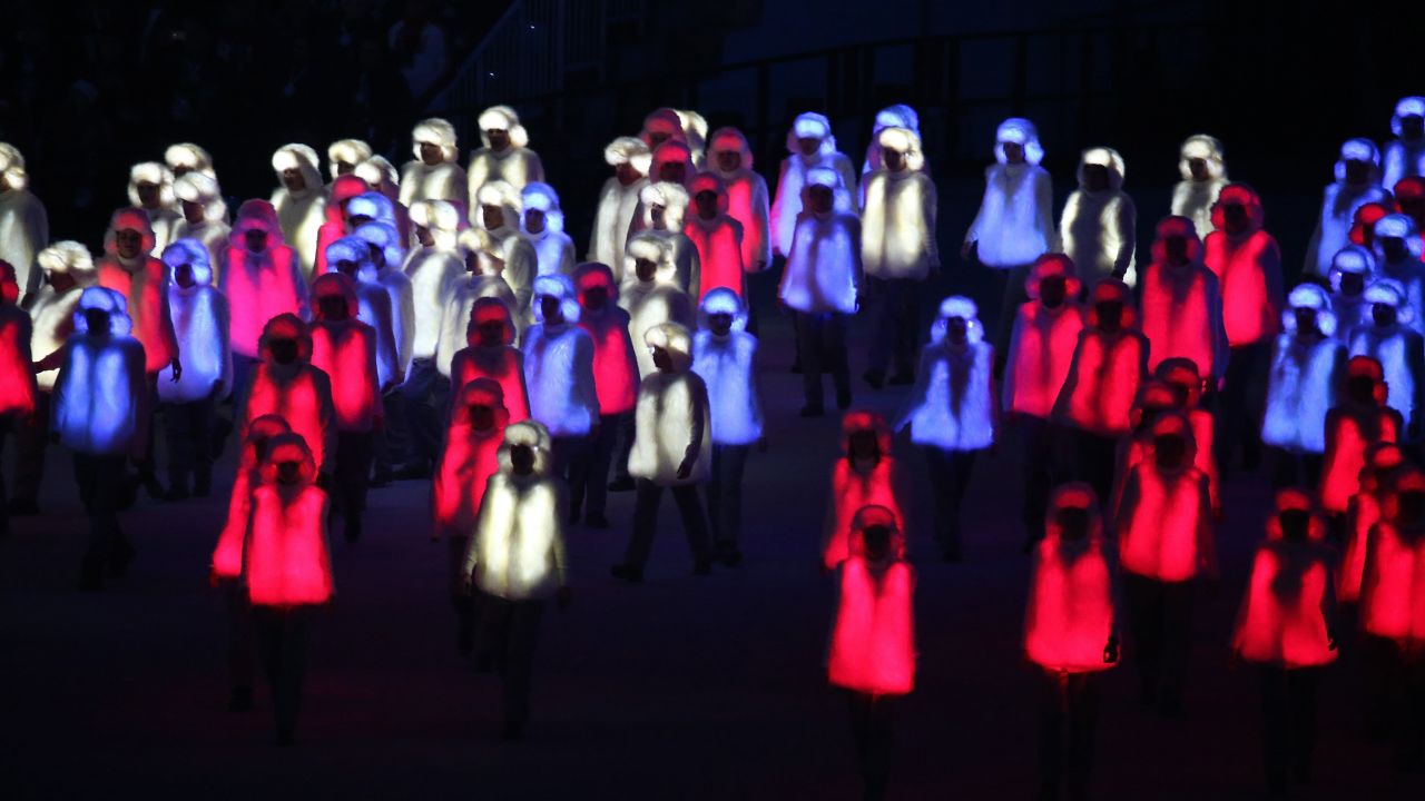 Performers in illuminated red, white and blue outfits prepare to form the Russian national flag.