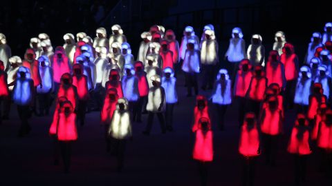 Performers in illuminated red, white and blue outfits prepare to form the Russian national flag.