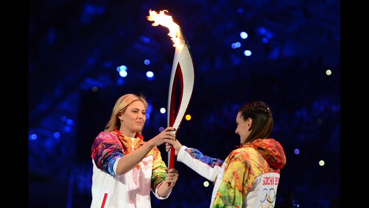 Russian tennis player and Olympic silver medalist Maria Sharapova, left, passes the Olympic torch to pole-vaulting legend Yelena Isinbayeva.