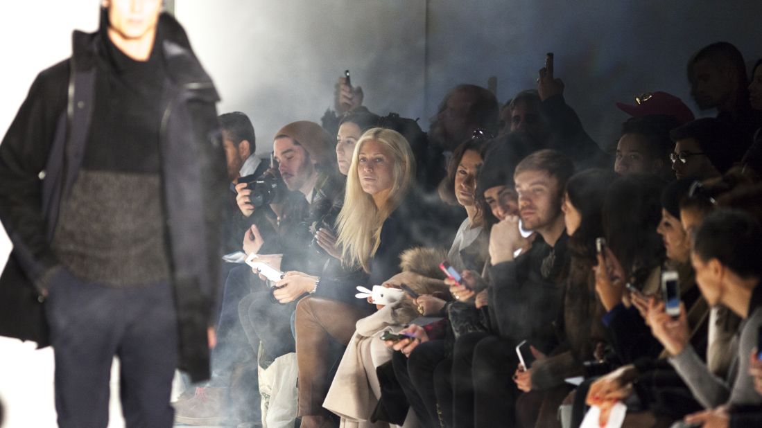 Audience members in the front row look on as a model displays a look by Nautica.