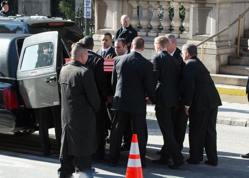Pallbearers lift Hoffman's casket into the back of a hearse.