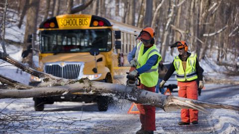 Workmen clear a downed tree blocking a school bus in the aftermath of a winter storm on Friday, February 7, in Downingtown, Pennsylvania. Utility companies scrambled to restore power to parts of the Northeast early Friday as hundreds of thousands shivered in the dark after a powerful snowstorm.