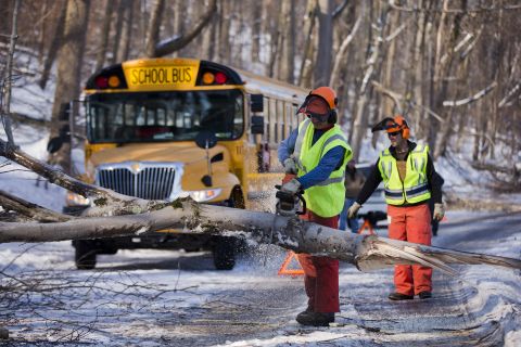 Workmen clear a downed tree blocking a school bus in the aftermath of a winter storm on Friday, February 7, in Downingtown, Pennsylvania. Utility companies scrambled to restore power to parts of the Northeast early Friday as hundreds of thousands shivered in the dark after a powerful snowstorm. 