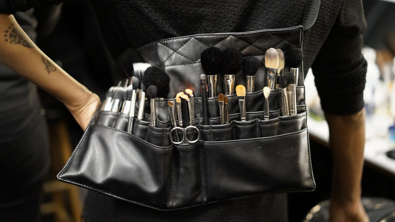 A makeup artist wears a brush apron belt for easy application.