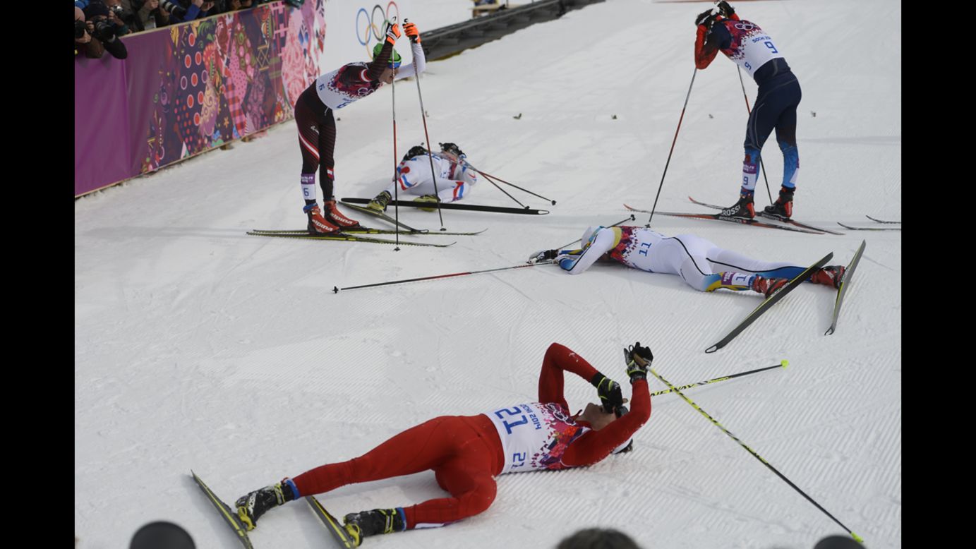 Swiss skier Dario Cologna, foreground, lies on the snow alongside other competitors in the men's skiathlon.