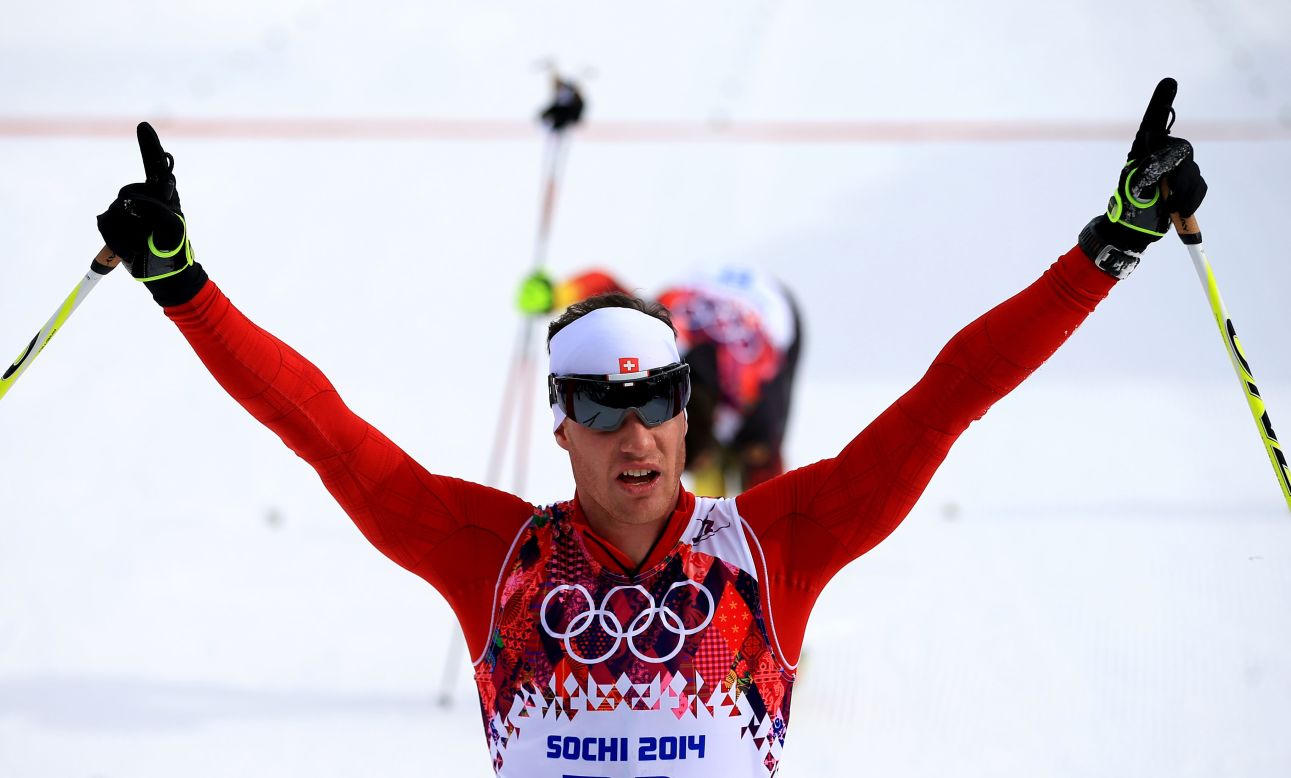 Dario Cologna of Switzerland raises his arms in triumph after taking gold in the men's skiathlon 15 km classic/15 km freestyle event.