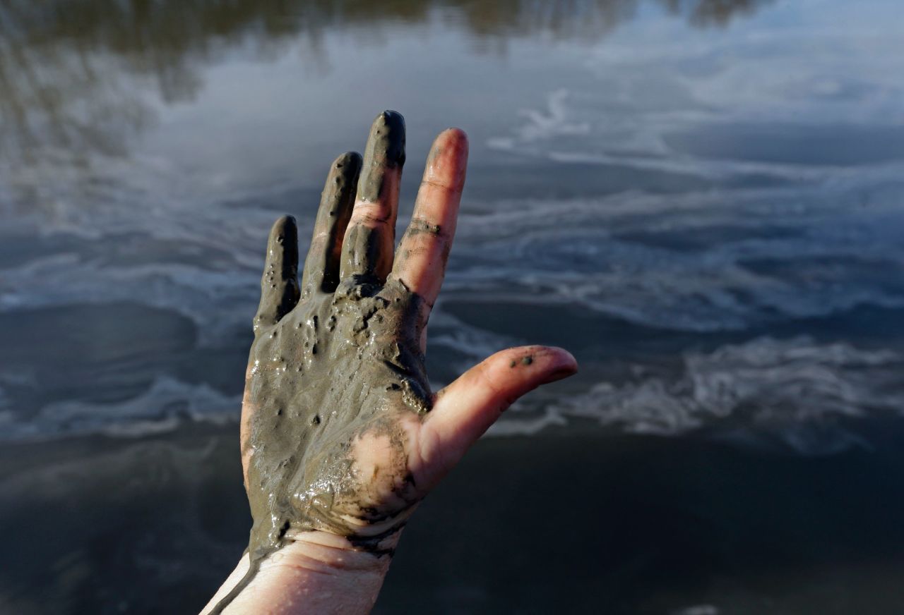 Amy Adams, North Carolina campaign coordinator with Appalachian Voices, shows her hand covered with wet coal ash from the Dan River on February 5. 