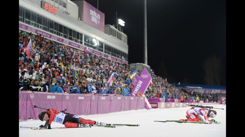 Canada's Megan Heinicke, left, and Poland's Monika Hojnisz collapse in the snow after competing in the 7.5-kilometer biathlon sprint on February 9.