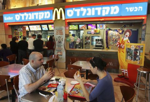 Israelis eat at a kosher McDonald's restaurant in Tel Aviv. After being pressured by Tel Aviv's Chief Rabbi, two of the city's McDonald's branches changed the color of their trademark signs to blue, indicating the availability of kosher food.