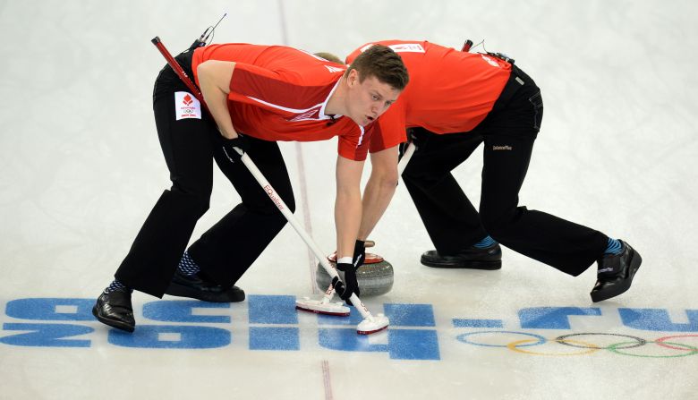 Denmark's Troels Harry, left, and Mikkel Poulsen sweep in front of a curling stone during a match against Russia on February 10.